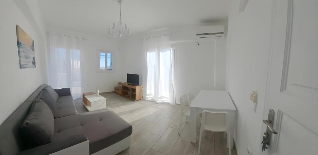 a white living room with a couch and a table at Moussa Erato in Agia Anna Naxos