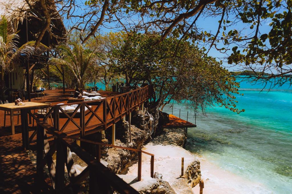 a beach with wooden benches and the water at Isla Única- Islas del Rosario in Isla Grande