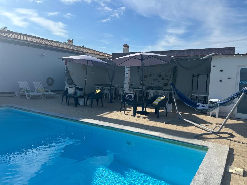 a swimming pool with a hammock and a table and chairs at Bungalow Azul Profundo in Palmela