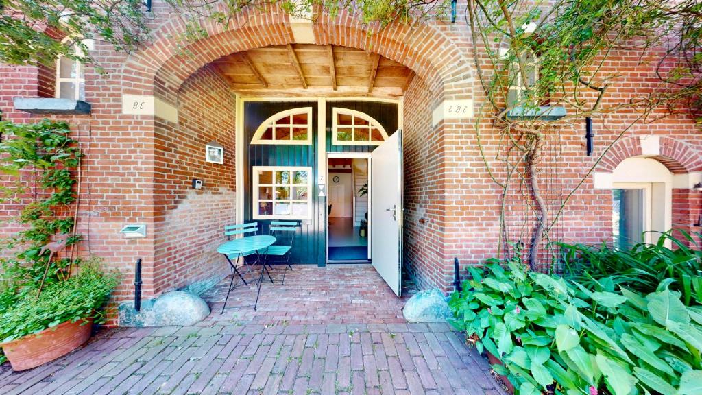 a brick building with a door and a table and chairs at Vakantie appartement Erve de Wezel in Diepenheim