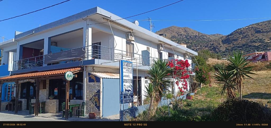 a white building with palm trees and mountains in the background at Jason Rooms & Studios in Keratokampos