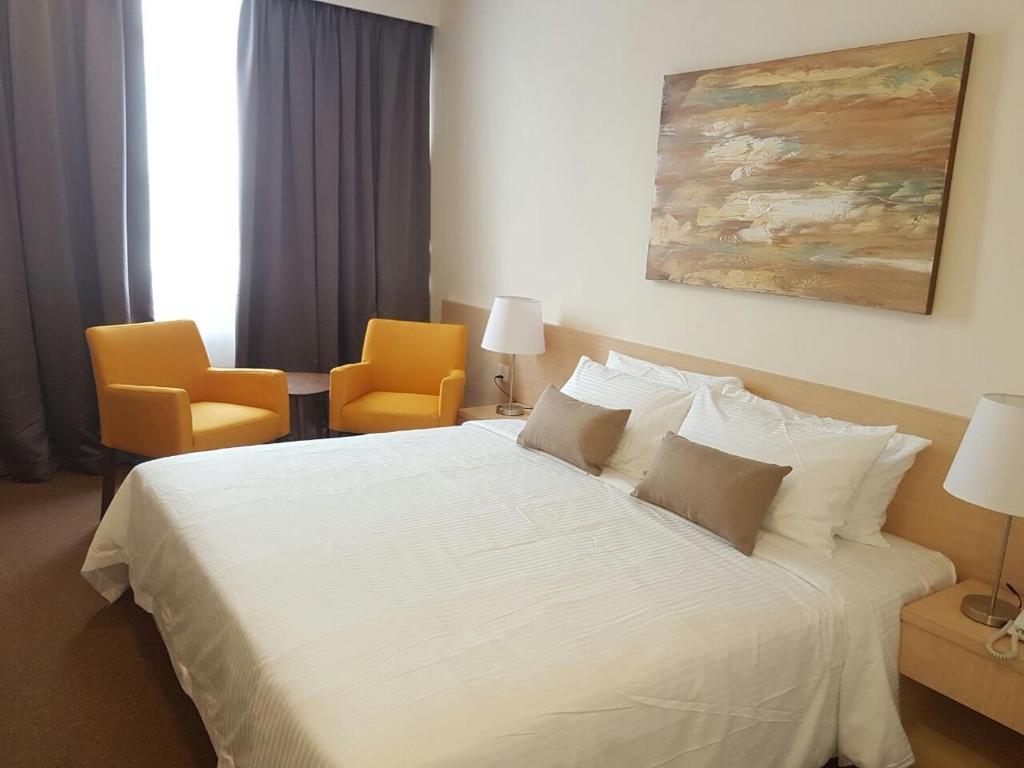 a bedroom with a white bed with two orange chairs at The View Hotel in Segamat