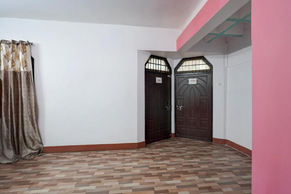 a hallway with two brown doors and white walls at SPOT ON Hotel prayag villa in Allahābād