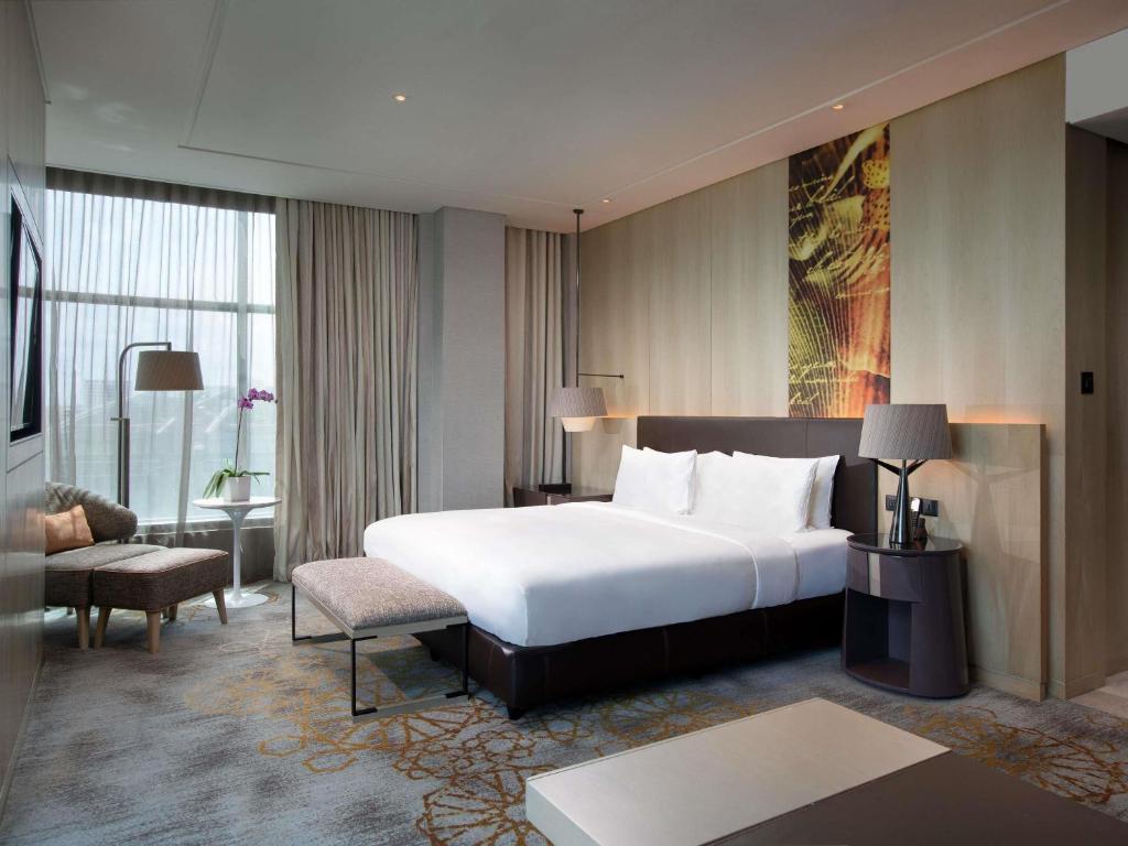 A polished king-style bedroom with a window-side seating area.