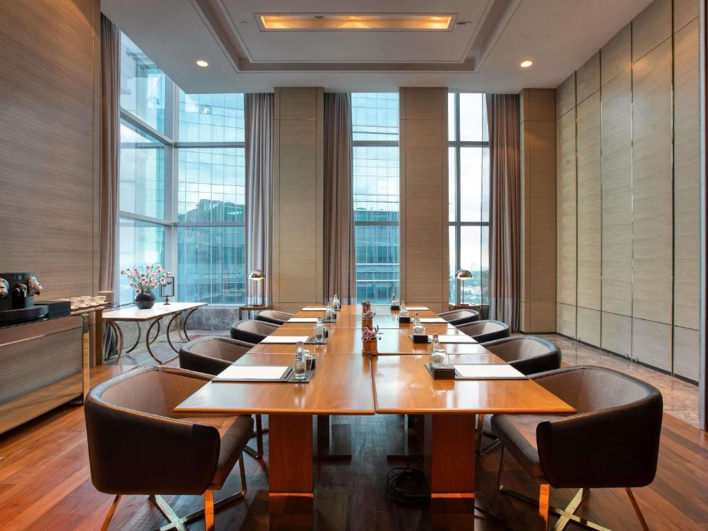 A sunlit boardroom with a polished wooden table and city-facing windows.