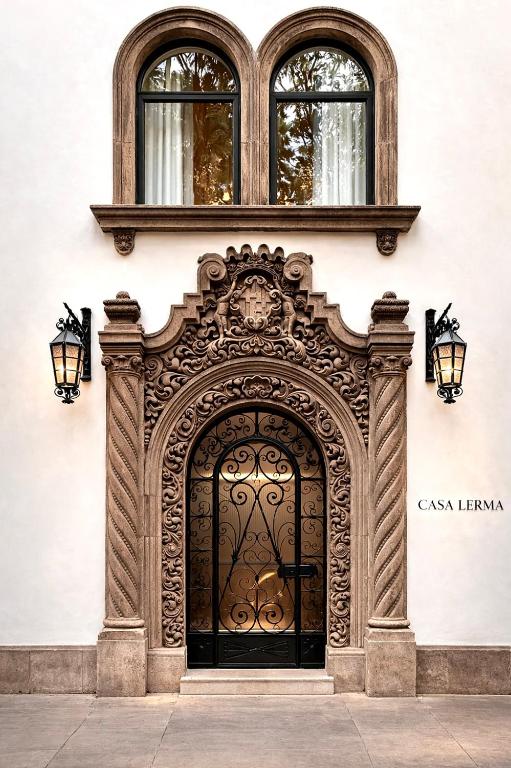 an ornate black door on a building with two windows at Casa Lerma in Mexico City