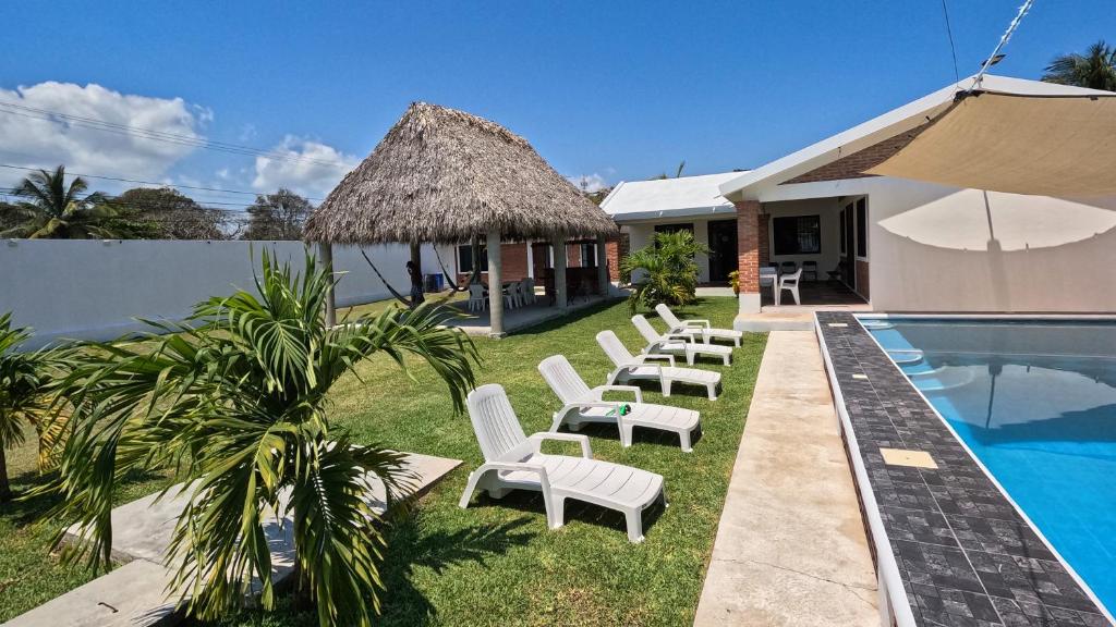 a group of white lounge chairs next to a swimming pool at Villa Esmeralda del Mar in Monte Gordo