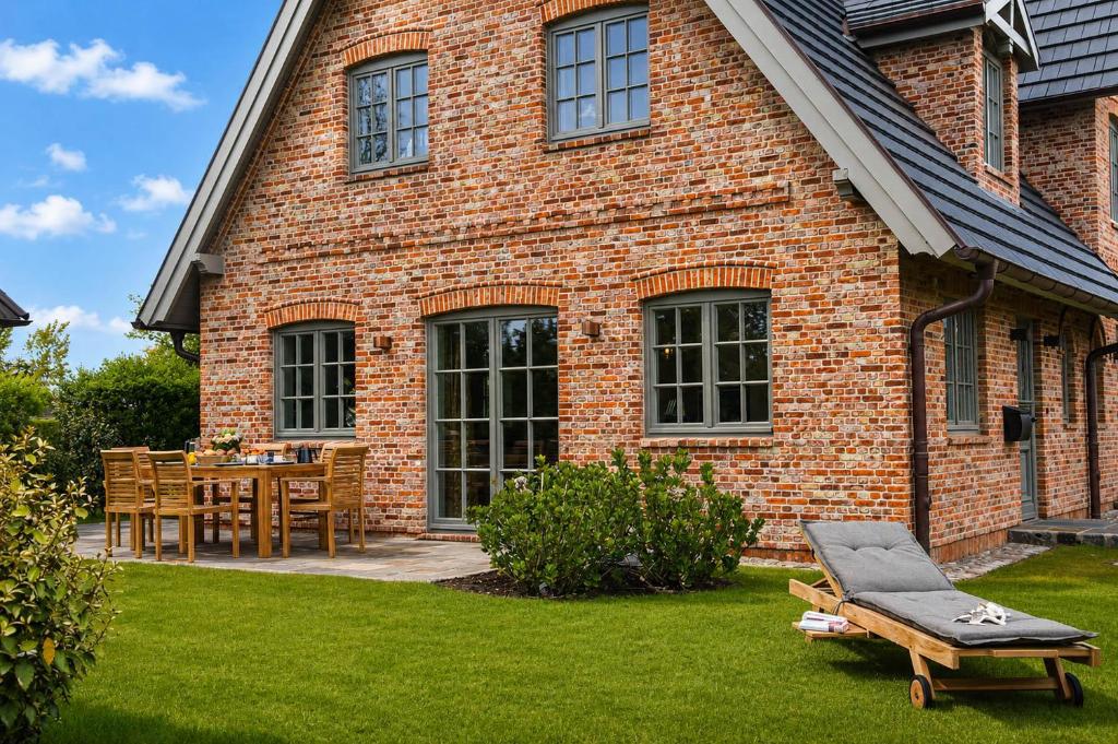 a brick house with a table and chairs in the yard at Haus Friesenkrone in Braderup
