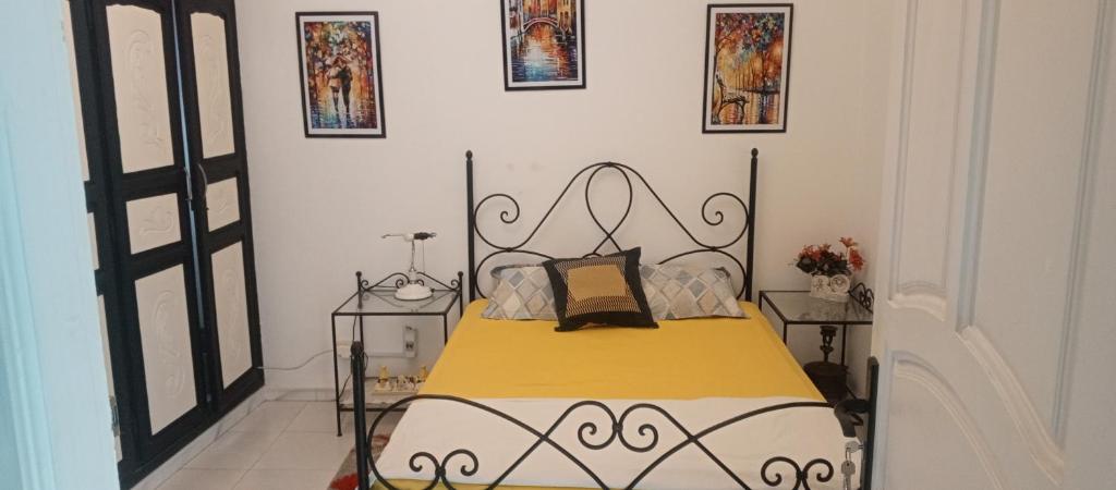 a bedroom with a bed with a yellow and white blanket at Appartement terrasse climatisée in Tunis