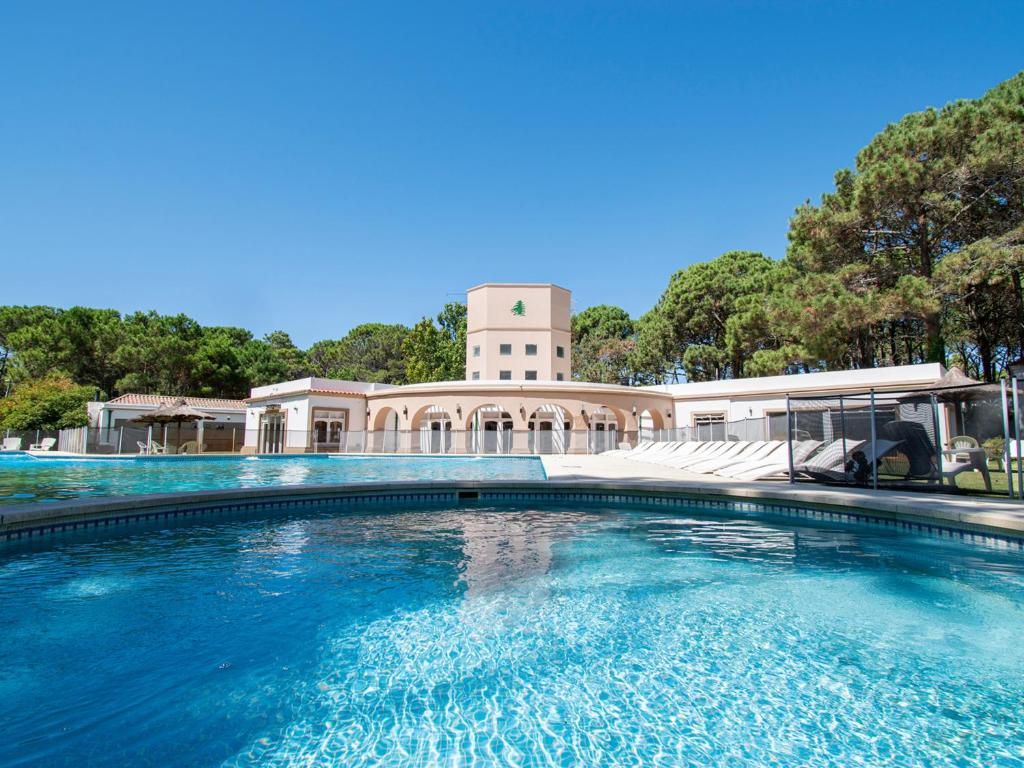 a swimming pool in front of a building with a clock tower at Del Pinar Apart in Costa del Este