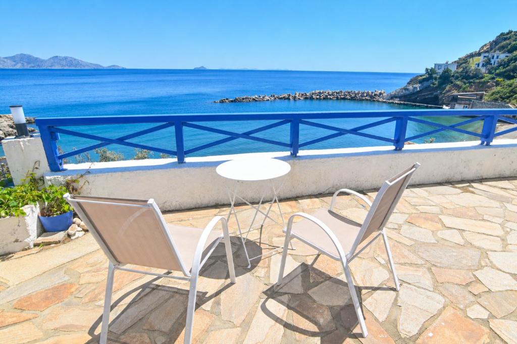 two chairs and a table with a view of the ocean at Ikaria Therma Blue in Agios Kirykos