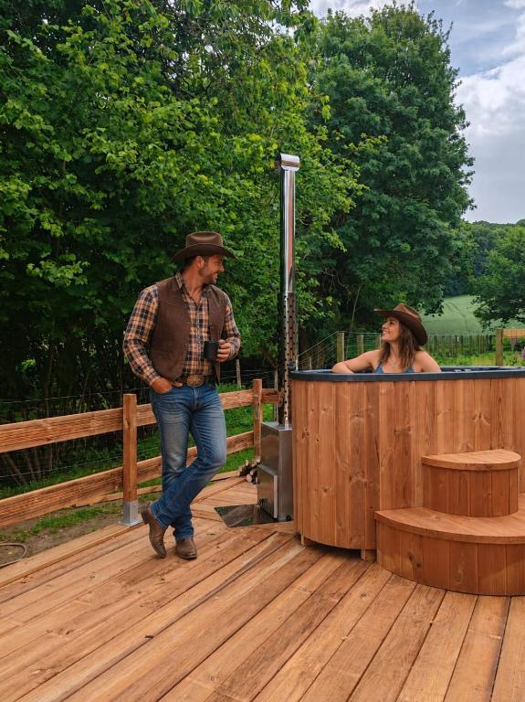 a man and a woman standing next to a hot tub at Les Ecuries du Ranch in Les Cresnays