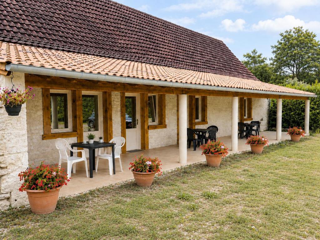 a house with a patio with a table and chairs at Chambres de l'Igues in Montfaucon