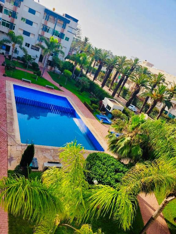 a large swimming pool with palm trees next to a building at The hidden oasis, steps from the beach and pool in Mohammedia