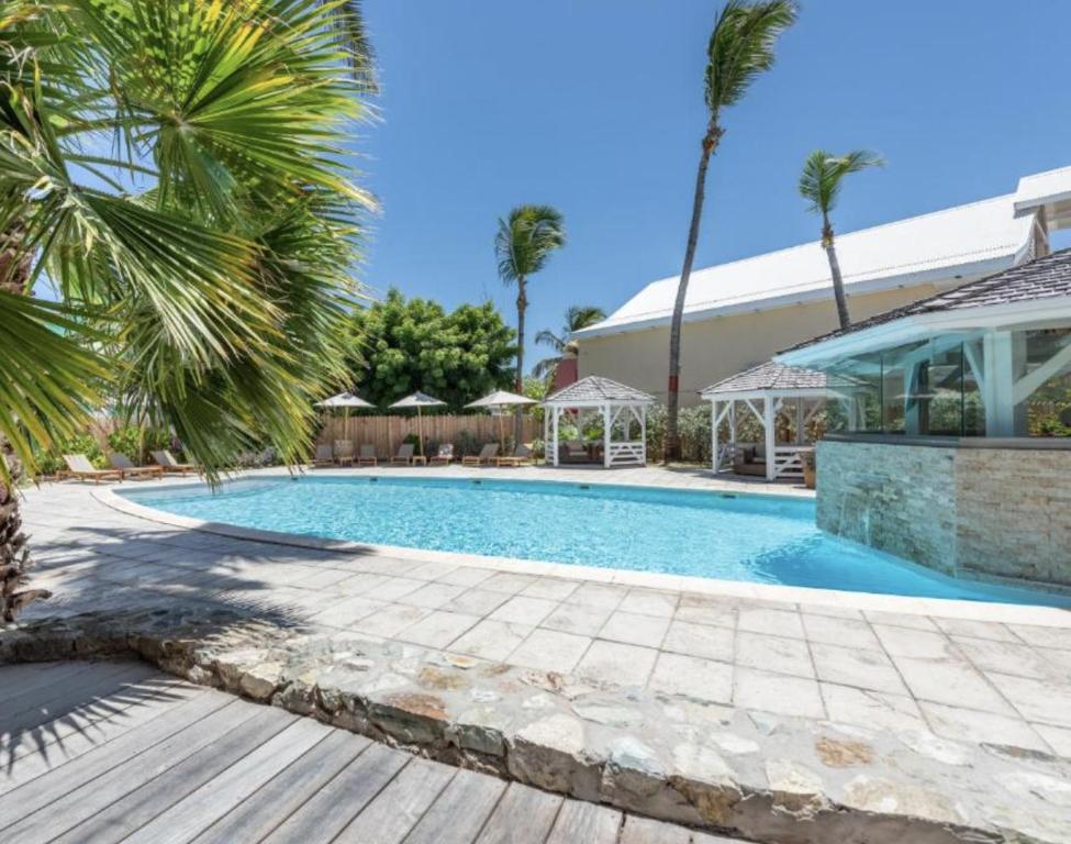 a swimming pool with palm trees and a house at Duplex La Plage Orient Bay in Orient Bay