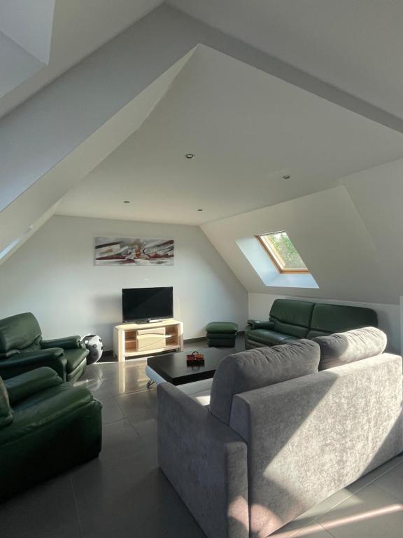a living room with a couch and a tv at LE BRIDGE in Bénouville