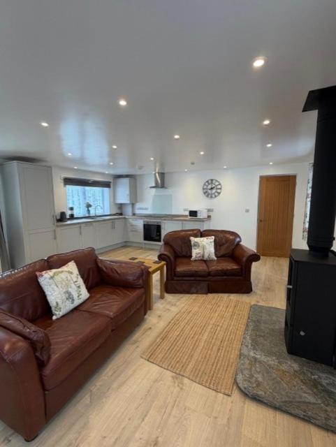 a living room with two leather couches and a kitchen at Pendragon Studio in Penzance