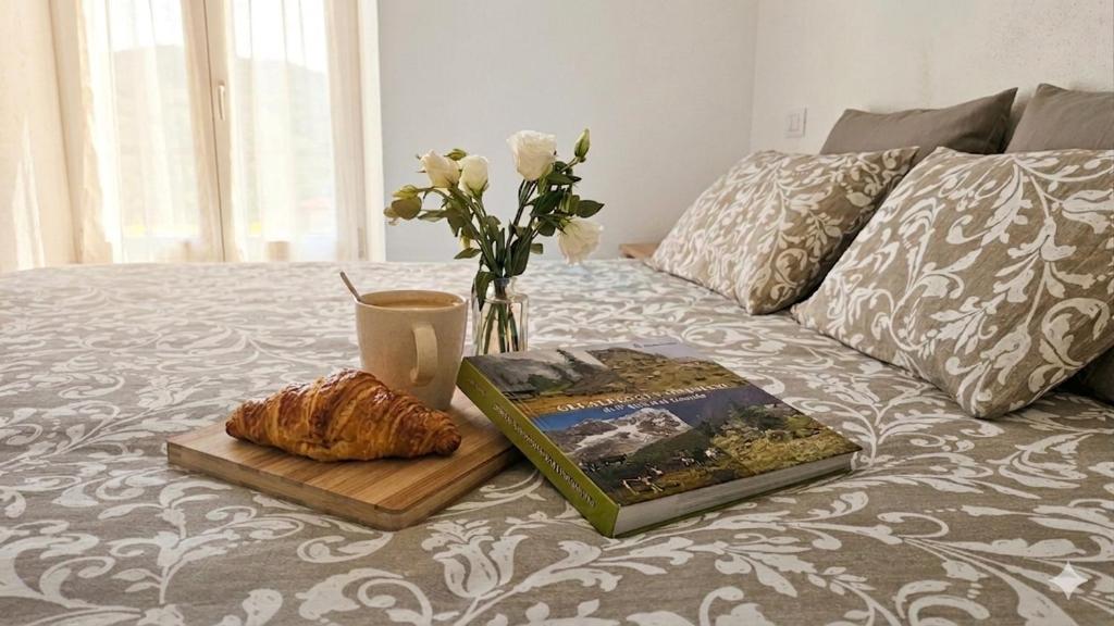 a table with a book and a vase of flowers on a bed at CA' VARADE di Martina Scarduelli in Varallo