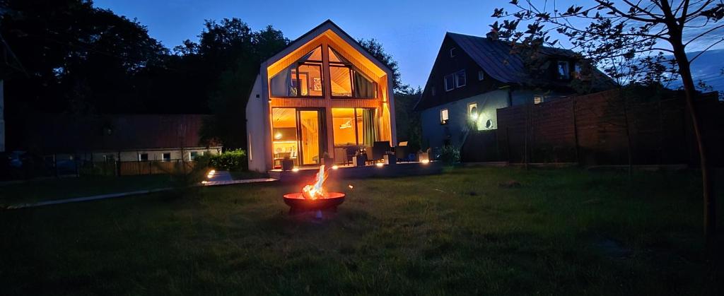 a small house with a fire in the yard at night at Hytte pod Karpaczem in Miłków