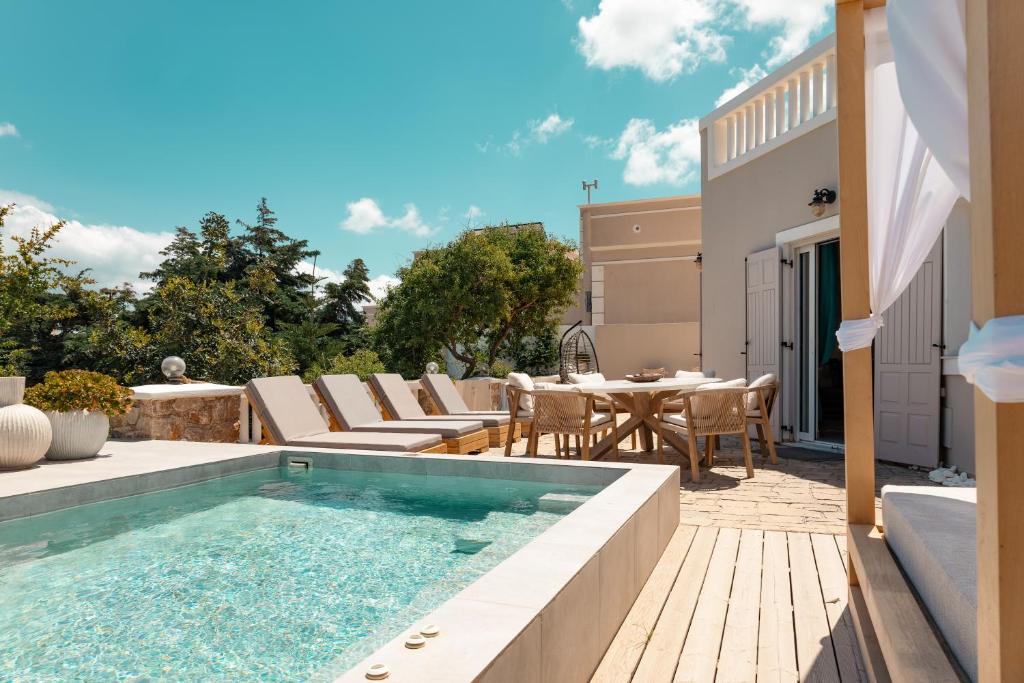 a backyard with a swimming pool and a table and chairs at Selenophile Villa with heated pool in Monolithos