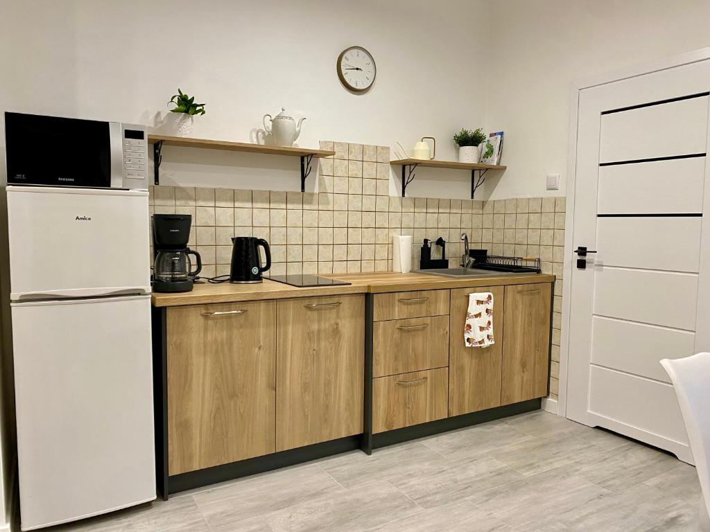 a kitchen with a white refrigerator and wooden cabinets at AT Apartament in Pasłęk