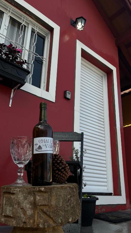 a bottle of wine sitting on a table next to a building at Chale Vermelho Aconchegante com lareira no bosque e estacionamento grátis in Extrema
