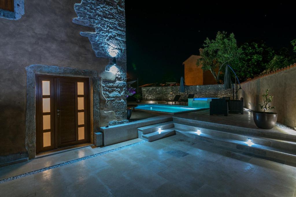 a patio with a door and a pool at night at Villa Sagri - heated pool in Žagrići
