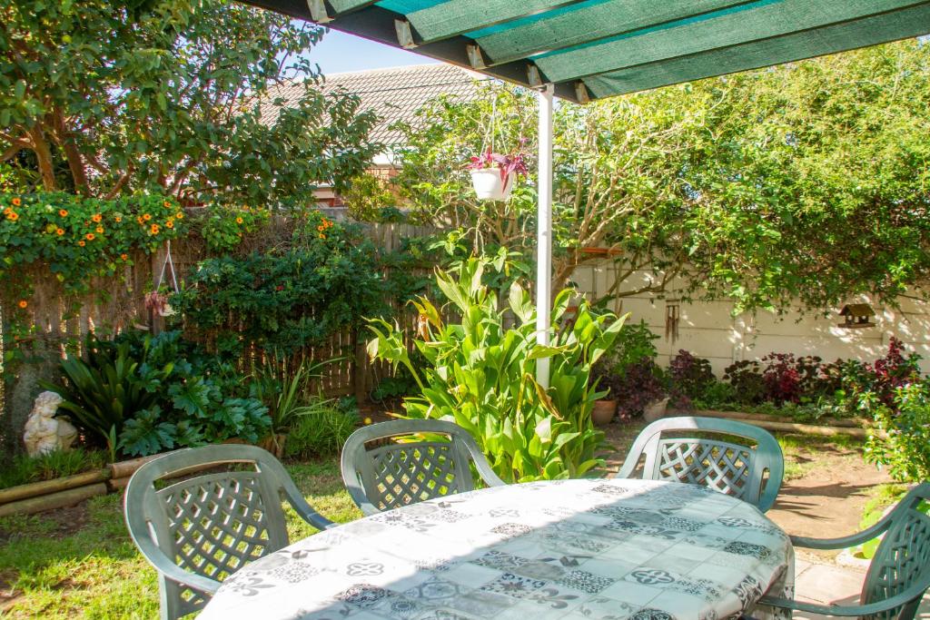 a table and chairs under an umbrella in a garden at Cote Cottage in Somerset West
