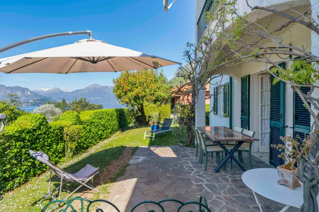 a patio with an umbrella and a table and chairs at Casa Donata by Gottschalk in Lierna