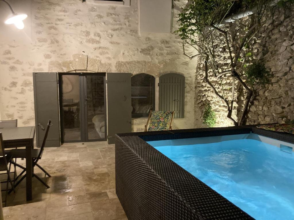a large swimming pool in a room with a table at La Grange de la Chèvre d'Or in Lagnes