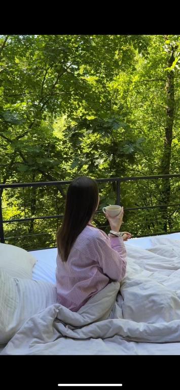 a woman sitting on a bed holding a vase at Furo Treehouse in Barajevo