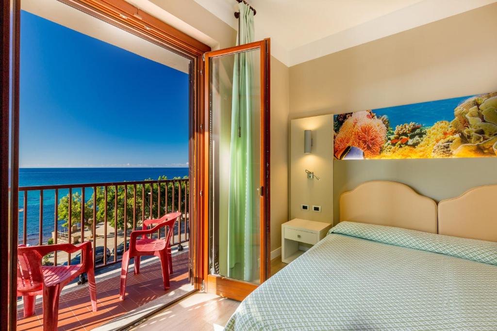 a bedroom with a bed and a balcony with the ocean at Hotel El Balear in Alghero