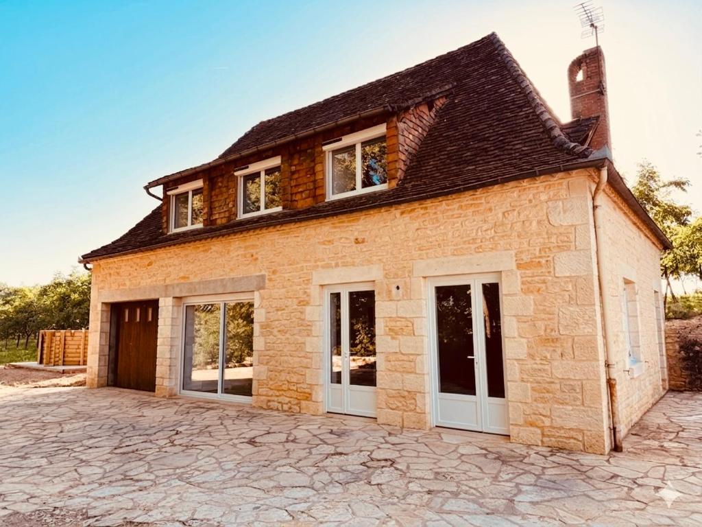 a brick house with white doors on a driveway at Gîte La Chaumière avec Piscine in Nailhac