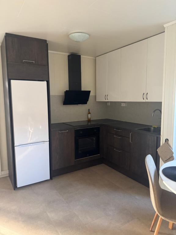 a kitchen with a white refrigerator and brown cabinets at Leilighet midt i sentrum in Kirkenes