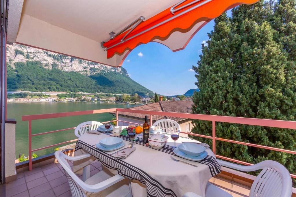 a table and chairs on a balcony with a view of the water at Casa Bader - Lake View Apt with Pool & Sauna - Happy Rentals in Riva San Vitale
