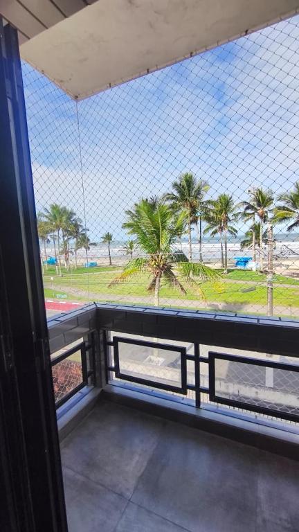 a balcony with a view of a beach with palm trees at Apê d'praia 31 - Beira Mar Bertioga in Bertioga