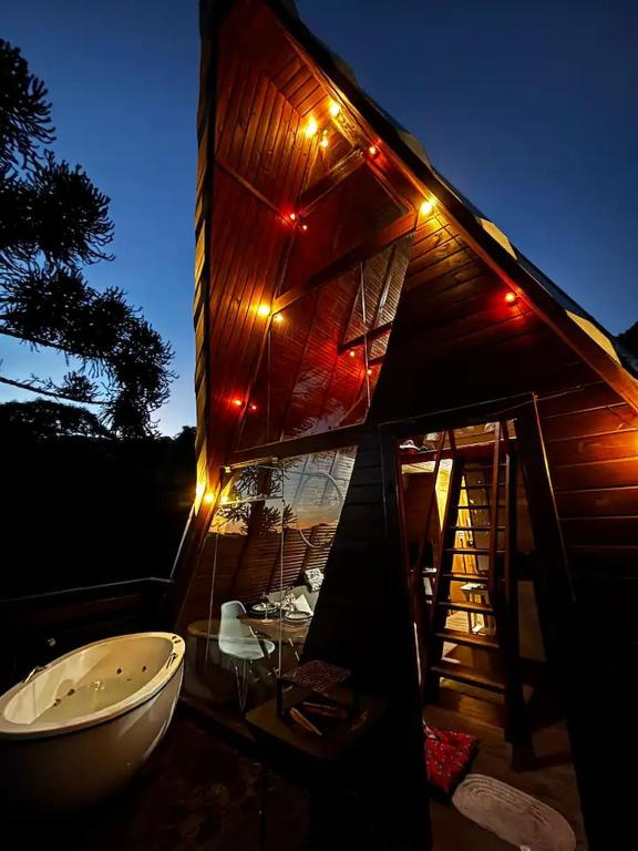 a tub sitting outside of a building with lights on it at Chalé Refúgio do Lobo in São Bento do Sapucaí