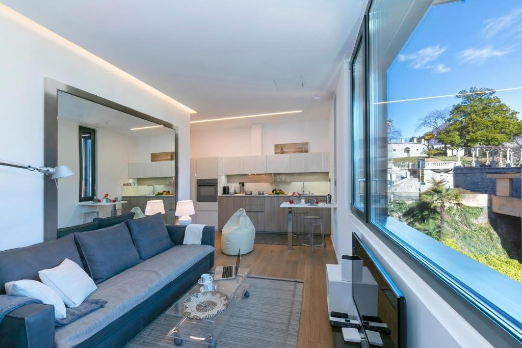 a living room with a blue couch and a large window at Casa Basilico with Lake View and Private Garage - Happy Rentals in Lugano
