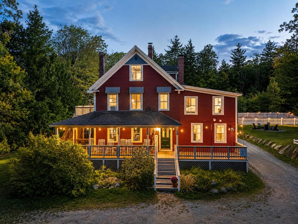 a large red house with its lights on at The Aurora Inn & Cottages in Bartlett