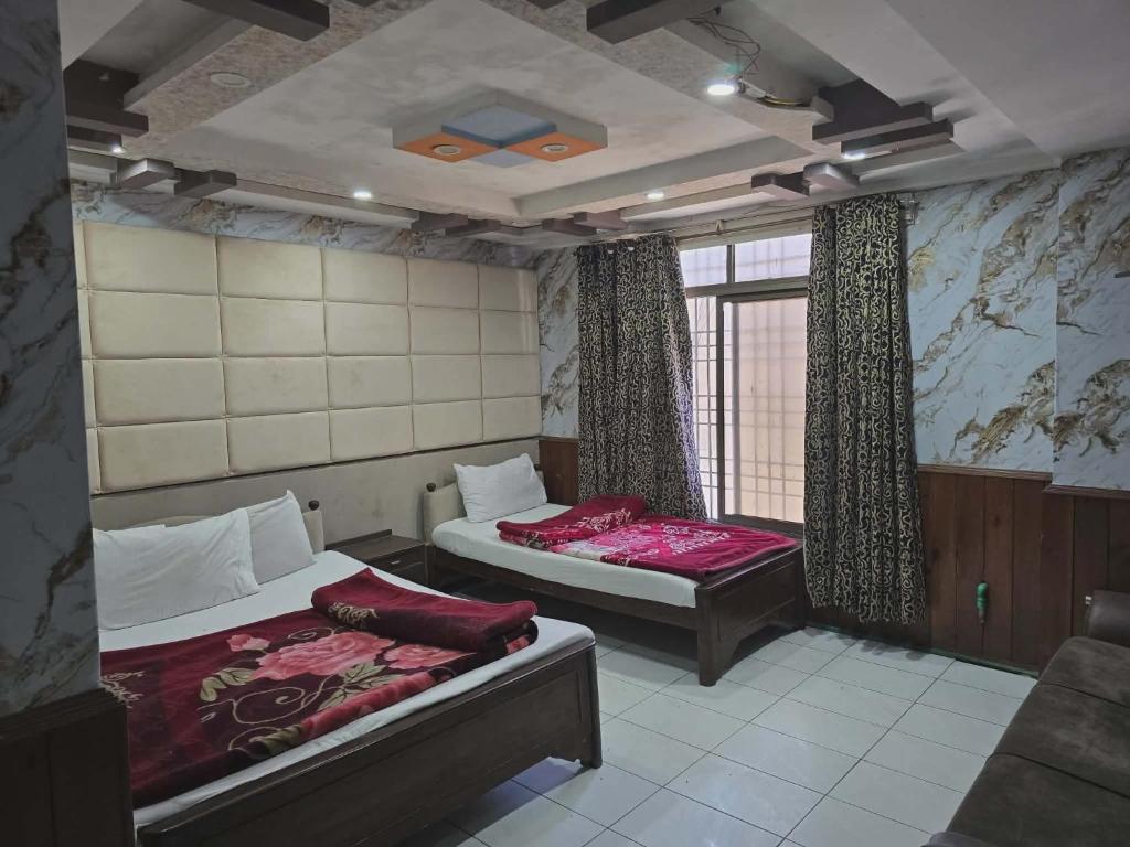 a room with two beds and a window at Mughal E Azam Hotel in Murree