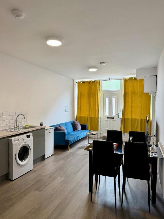 a living room with a blue couch and a table and chairs at Accessible Town Centre 1 bed Flat Kettering Wi-FI in Kettering