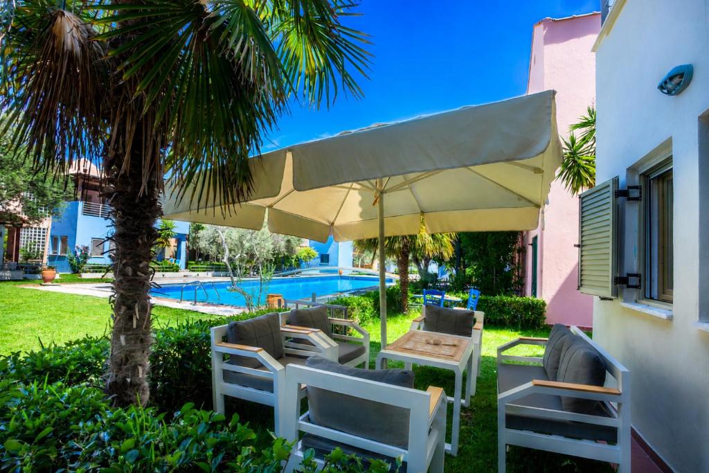 a patio with a table and chairs under a large umbrella at Villa Portoblue Pearl in Pefkochori