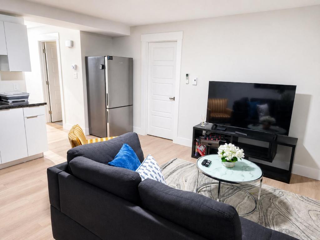 a living room with a black couch and a tv at Quiet Haven - One-Bedroom Suite in Riverview