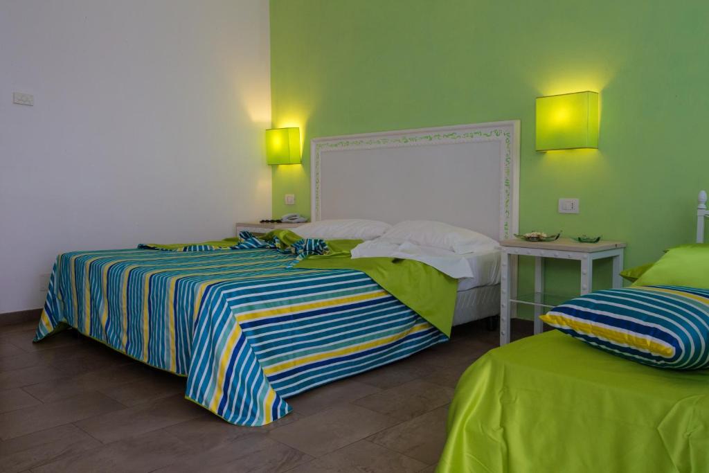two beds in a room with green walls at Hotel O'scià in Lampedusa