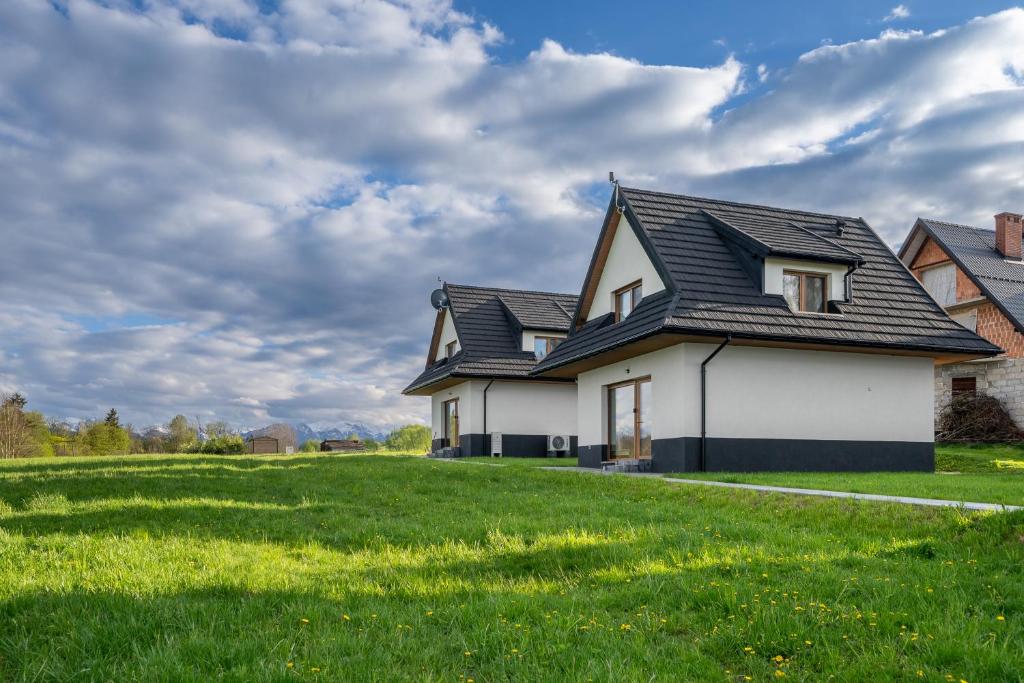 a house with a black roof on a green field at Biała Owca in Biały Dunajec