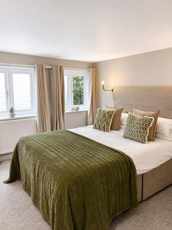 a bedroom with a large bed with a green blanket at The Raven Suites in Much Wenlock