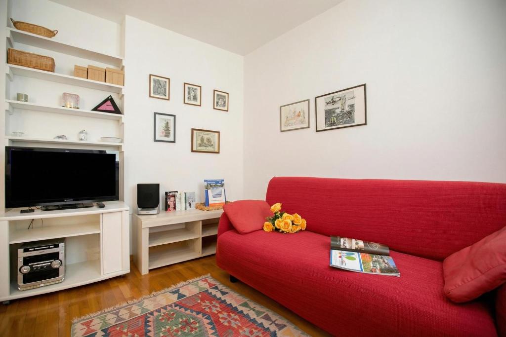 a living room with a red couch and a tv at Appartamento Centro Storico Riva 2 - Happy Rentals in Riva del Garda