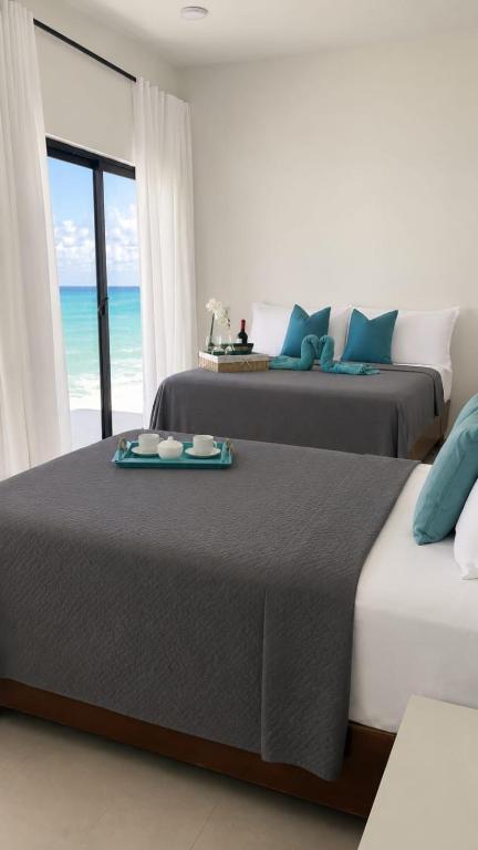 two beds in a bedroom with a view of the ocean at Privanza Hotels in Santa Cruz de Barahona