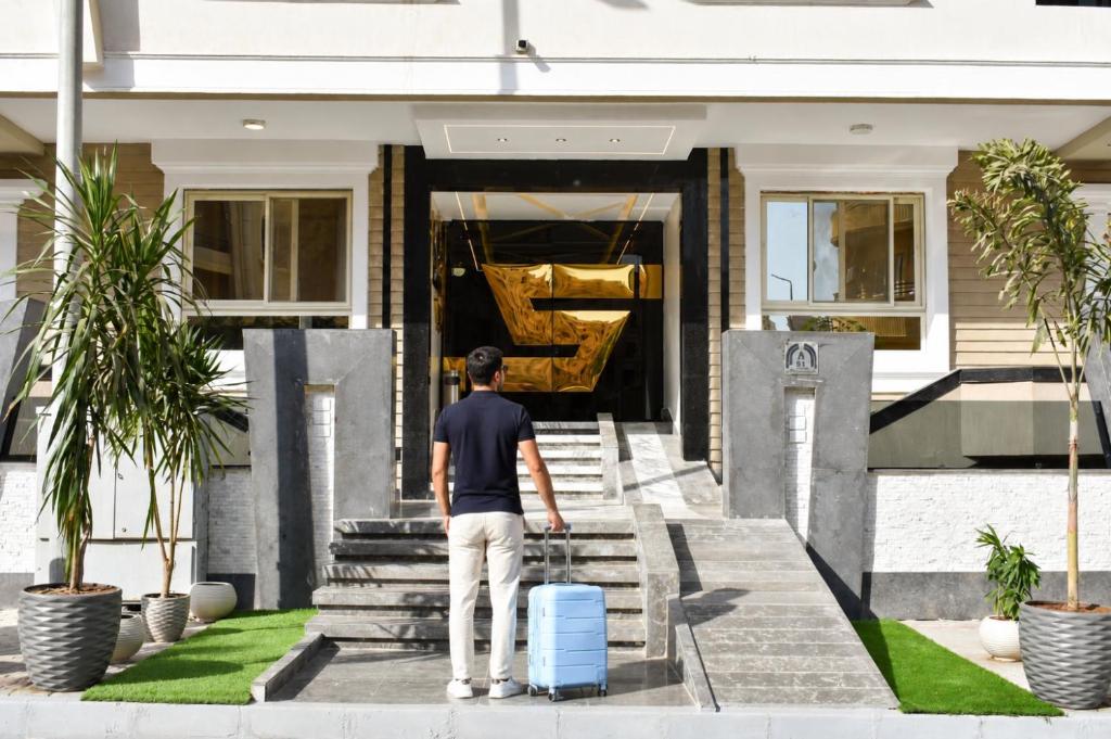 a man with a suitcase walking up the stairs to a house at Stay Inn 51 Hotel Zayed in Sheikh Zayed