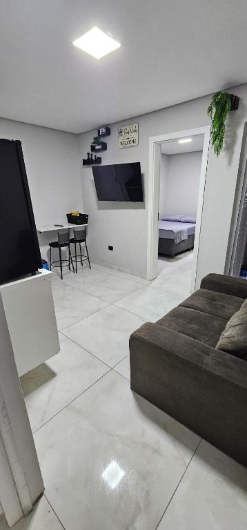 a living room with a couch and a tv and a table at RG Kitnet05 in Curitiba
